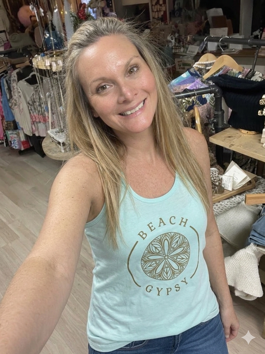 Woman wearing a light blue tank top with 'Beach Gypsy' print in a store setting.