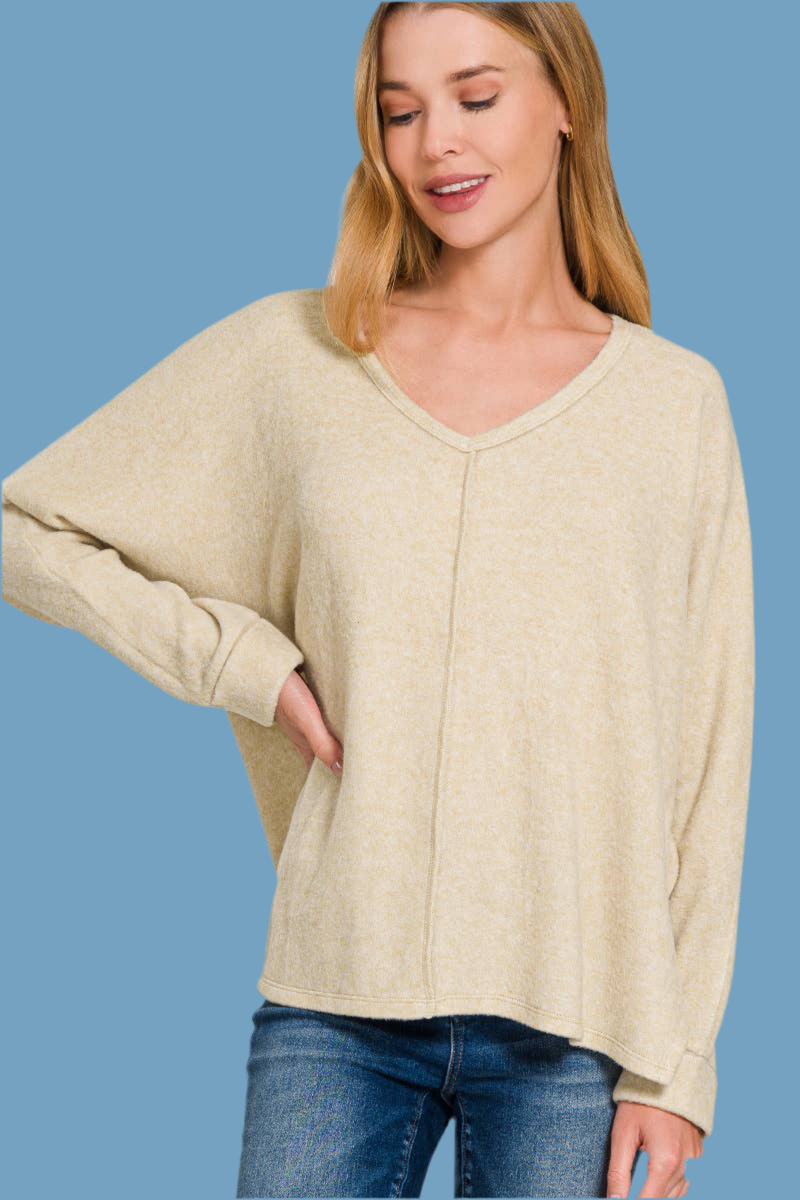 Woman wearing soft beige colored  sweater with long sleeves and a v-neck