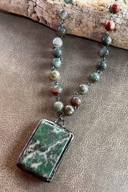 Necklace with green marbled pendant on a textured surface