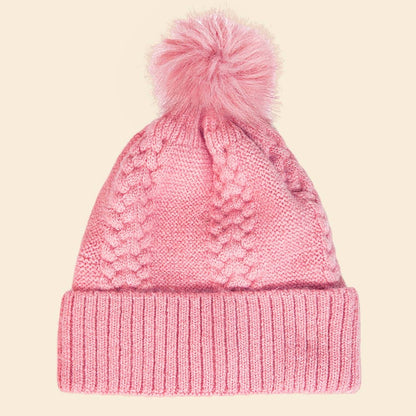 Pink knitted beanie with a pom-pom on a beige background
