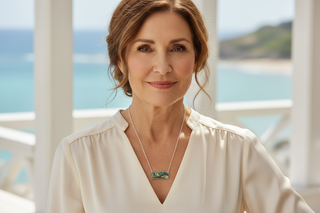 Woman wearing anabalone rectangle pendant necklace with a scenic water background