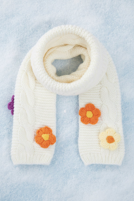 White knitted scarf with colorful flower patterns on a snowy background
