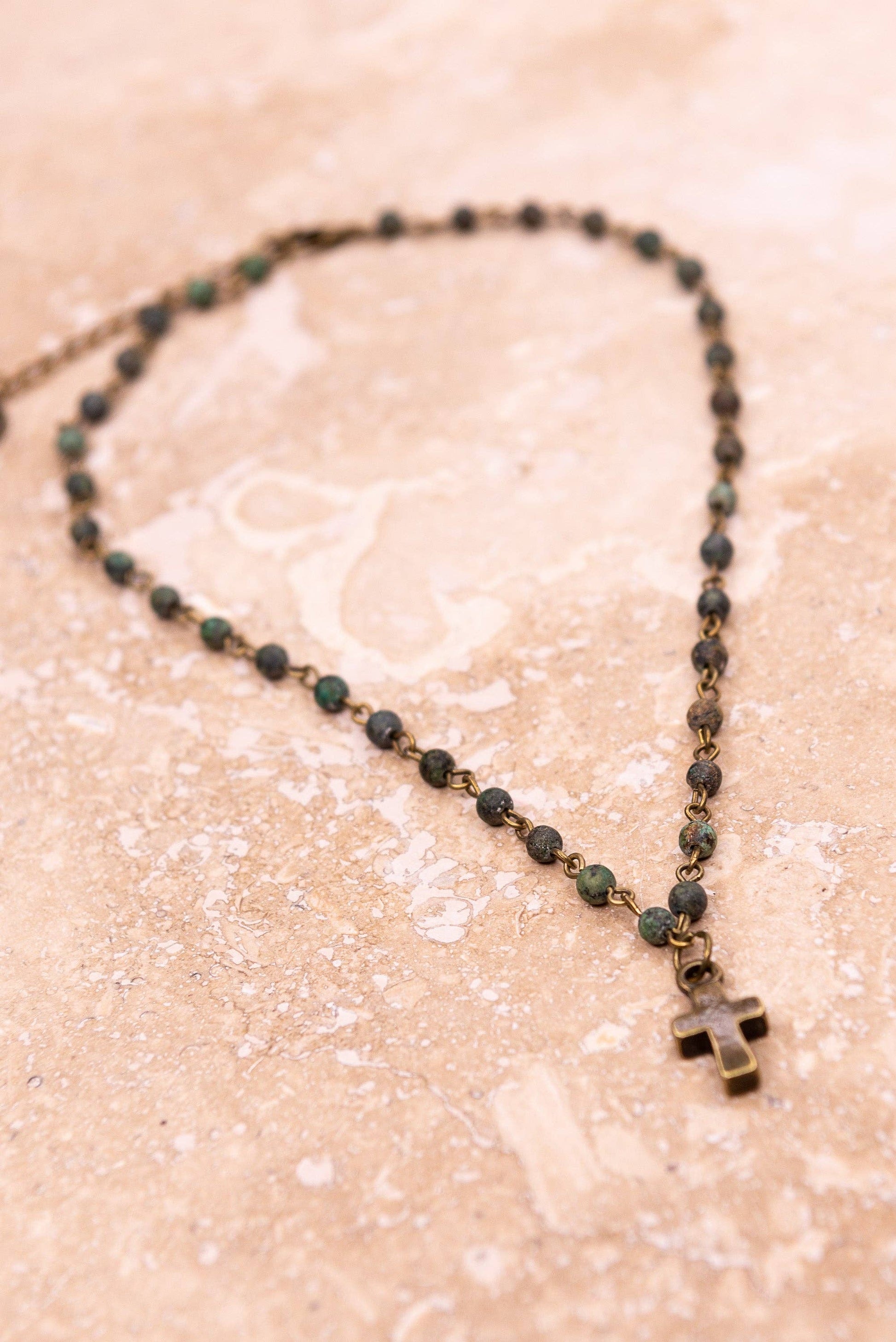necklace with a cross pendant on a beige surface