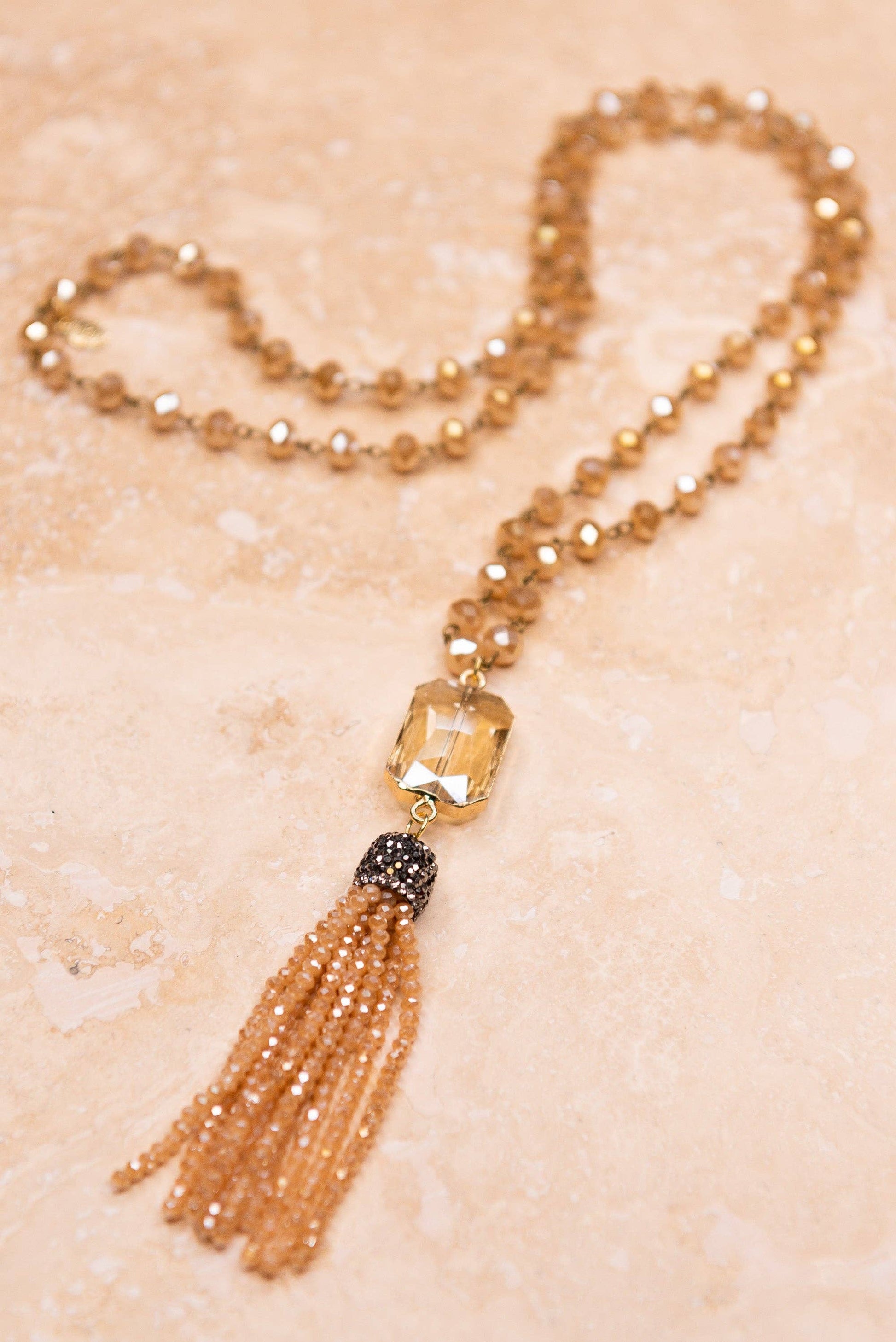 Necklace with beads and tassel on a textured beige background