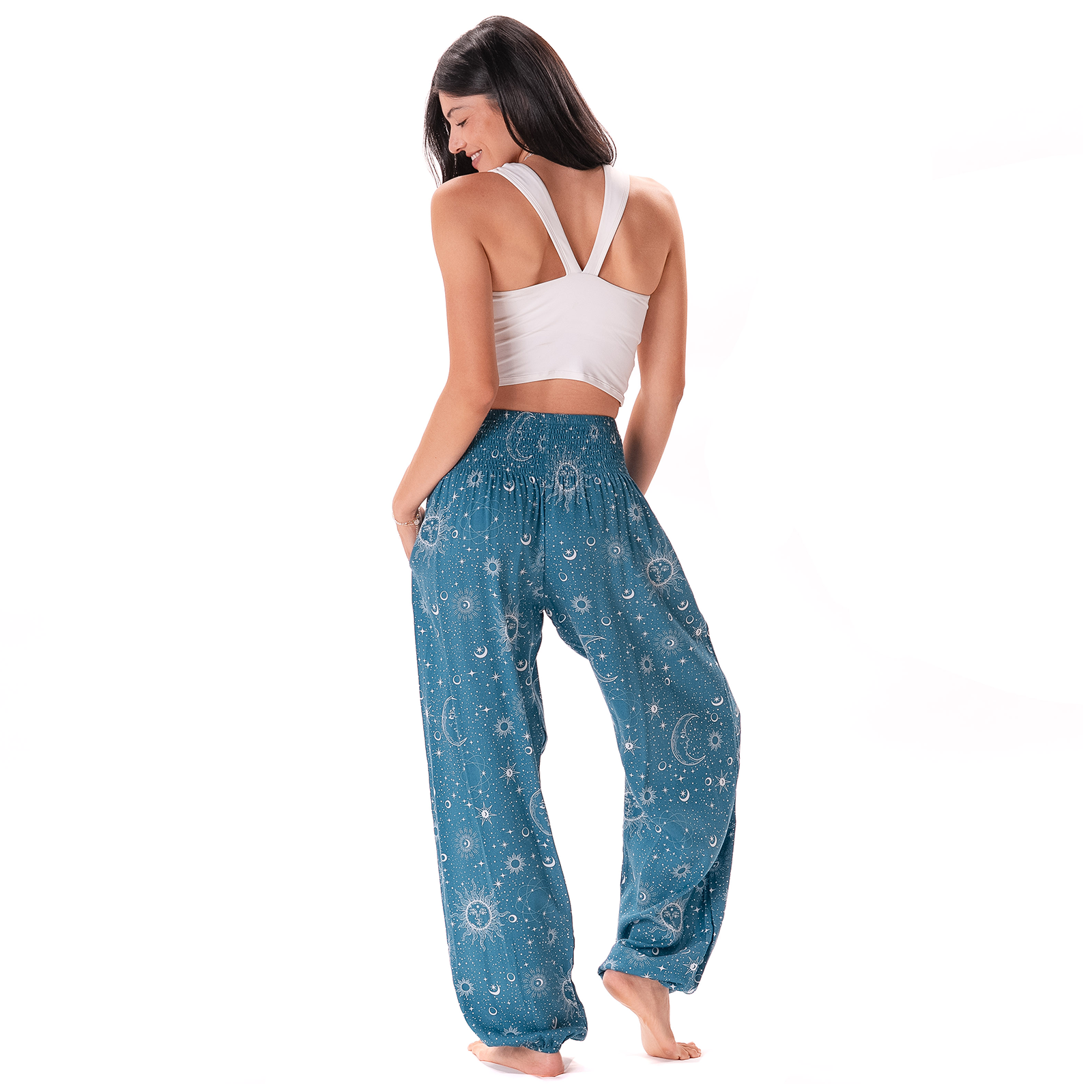  Ack view of Woman wearing blue patterned Cosmic Sun pants and a white top on a white background
