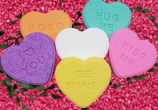 Colorful heart-shaped conversation candies on a pink glittery background