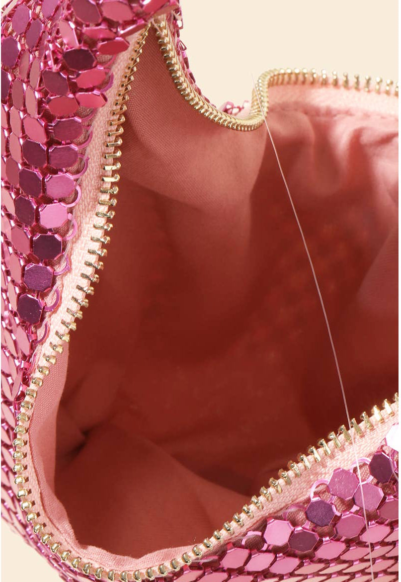 Close-up of a pink sequin clutch with gold zipper on a beige background