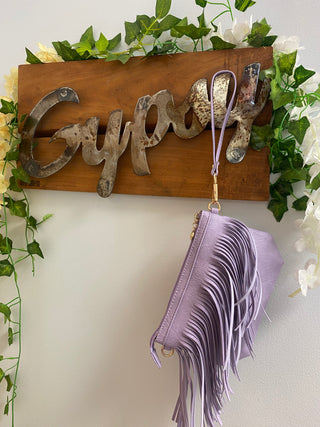 violet fringe crossbody bag hanging from gypsy sign