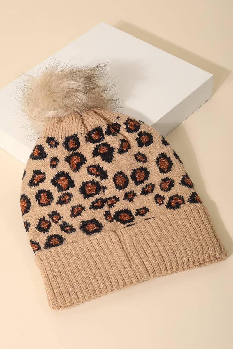 Leopard print beanie with fur pom-pom on a beige background