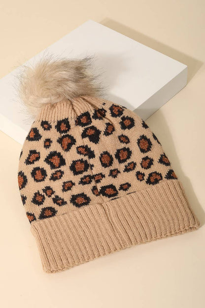 Leopard print beanie with fur pom-pom on a beige background