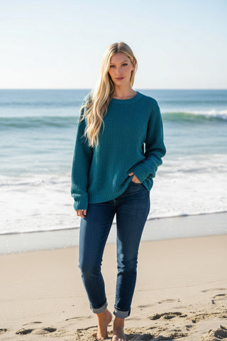 Woman wearing a teal sweater  on a BEACH background