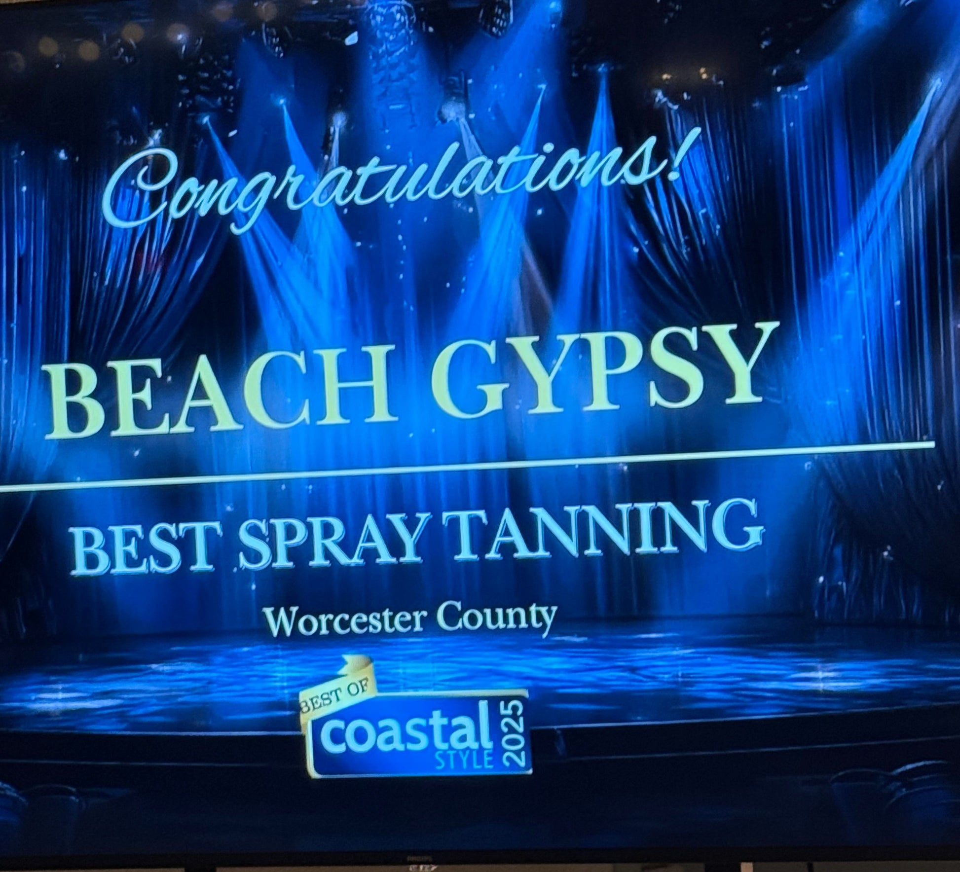 Blue sign with text 'Beach Gypsy' and 'Best Spray Tanning' awarded by Coastal Style for Spray Tanning in Worcester Count, MD