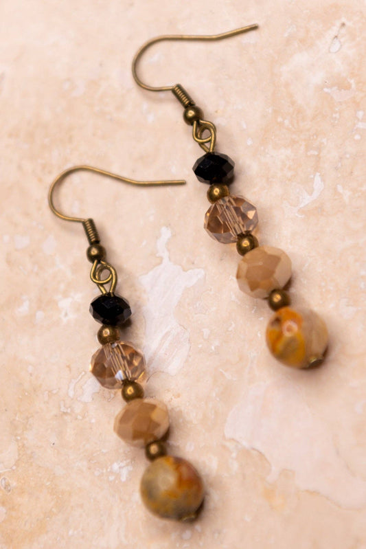 Pair of beaded earrings on a textured beige surface