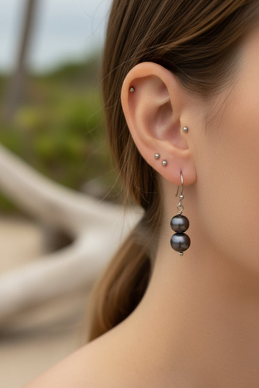 Black pearl earrings on a woman’s ear