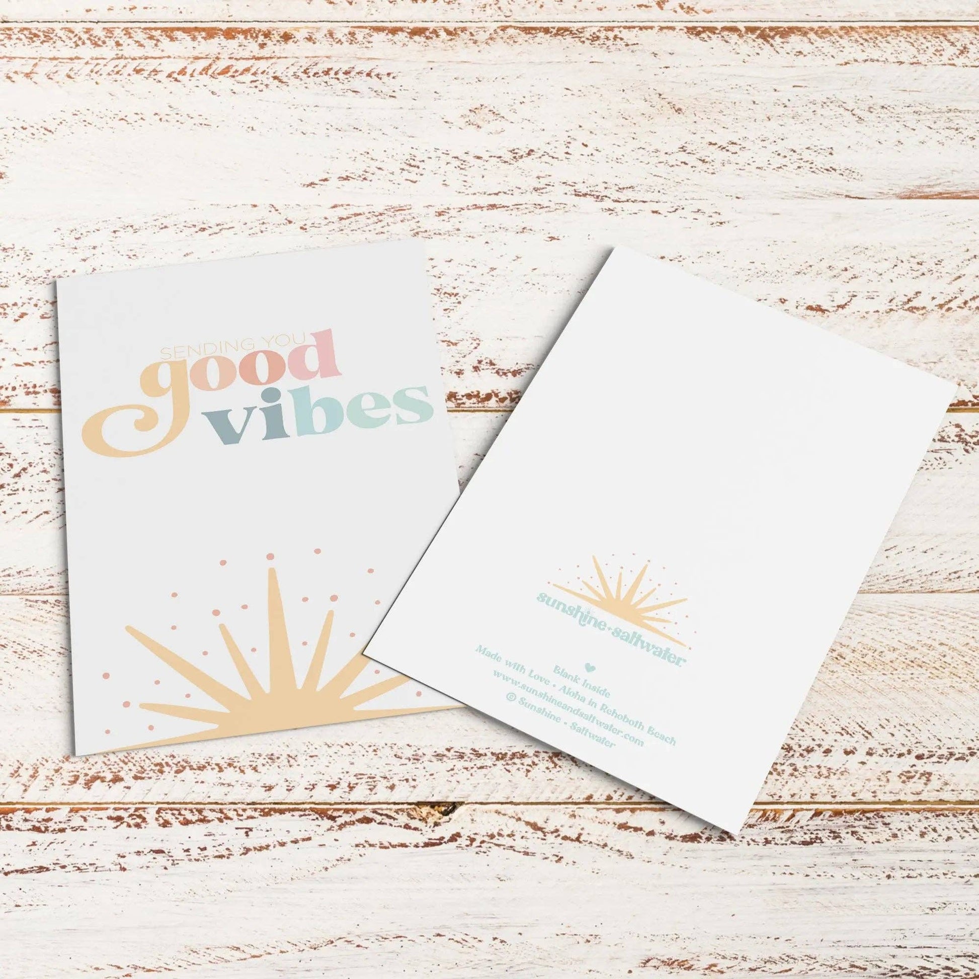 Two greeting cards on a wooden surface with 'good vibes' text.