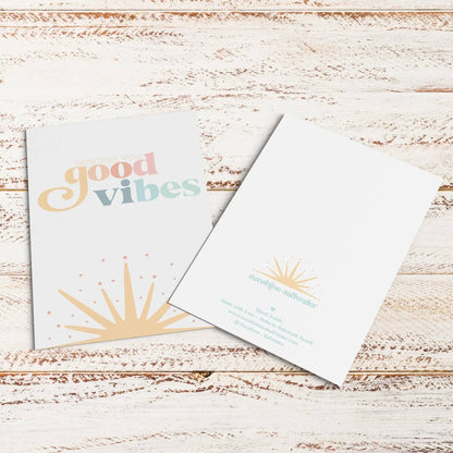 Two greeting cards on a wooden surface with 'good vibes' text.