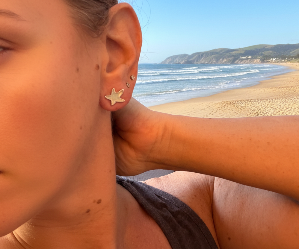 Starfish earrings on woman with a beachy background 