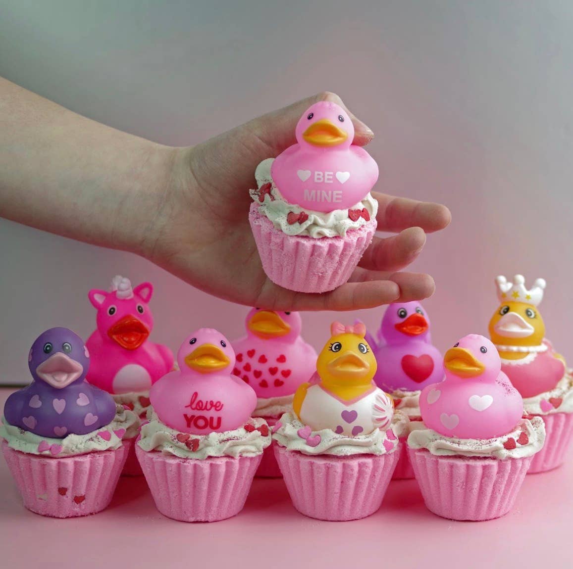 Pink duck-shaped cupcakes with decorative elements on a pink surface