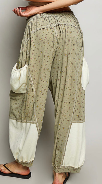 Back view of Woman wearing flowing sage colored ditzy flower print pants with cream patch pockets