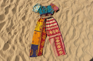 Colorful patterned top and pants on sand background 