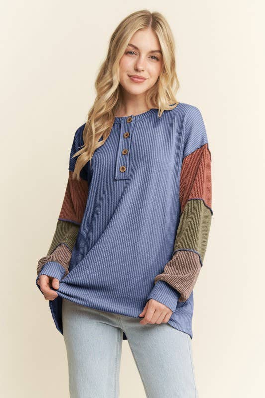 Woman wearing a blue and brown color-blocked sweater on a beige background