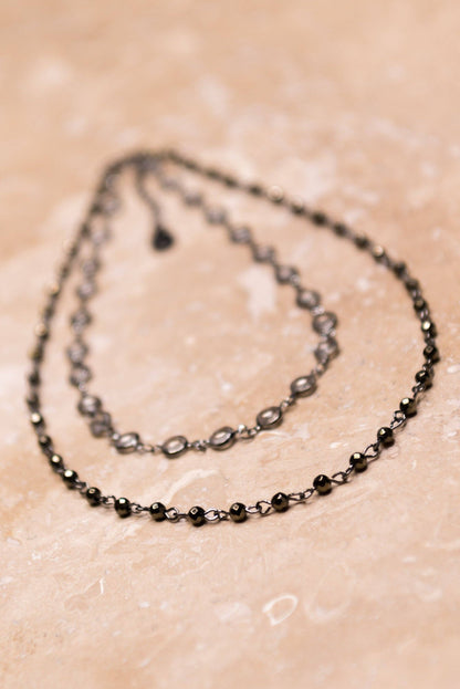 Two black beaded necklaces on a beige surface