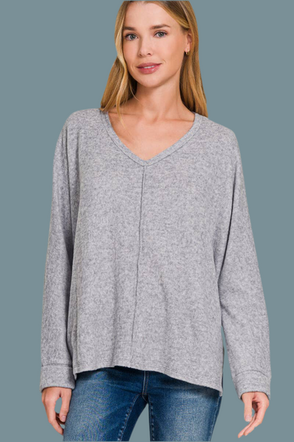 Woman wearing soft grey sweater with long sleeves and a v-neck