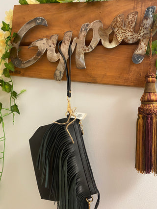 black fringe crossbody bag hanging from gypsy sign