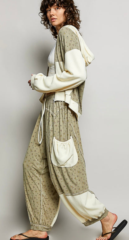 Woman wearing flowing sage colored ditzy flower print pants with cream patch pockets Side view