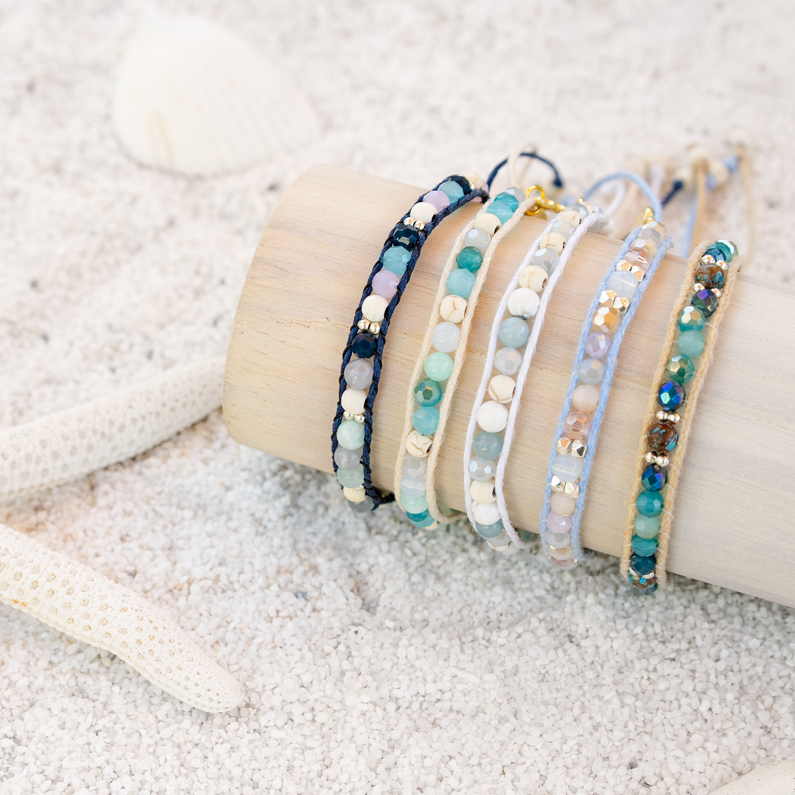 Set of beaded bracelets on a wooden block with sand in the background