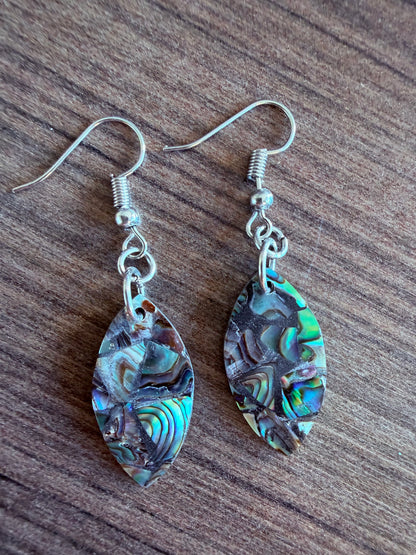Pair of abalone shell earrings on a wooden surface