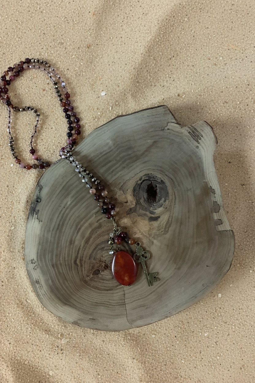 Orange  and red long beaded necklace with large stone and key pendants.