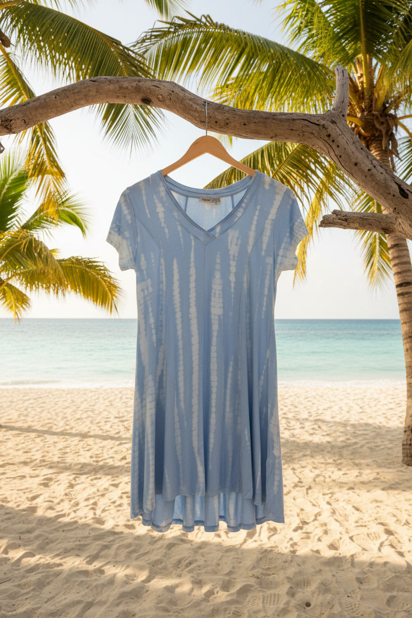 Blue tie dyed dress hanging from a tree branch on a sandy beach