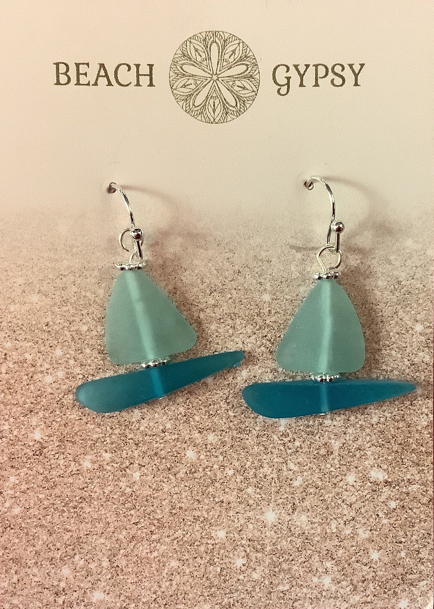 Seaglass sailboat  earrings on a 'Beach Gypsy' branded card against a pink background