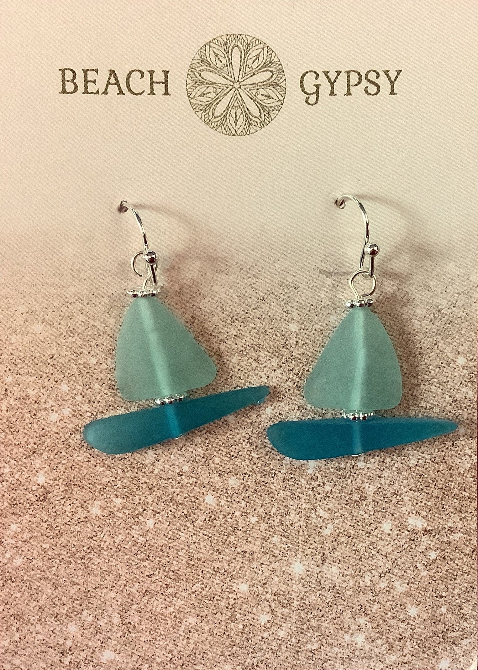 Seaglass sailboat  earrings on a 'Beach Gypsy' branded card against a pink background