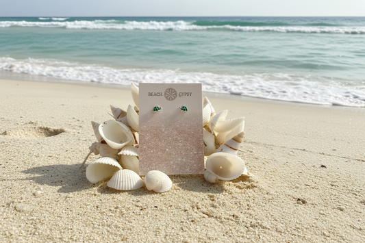 Turtle earrings on beach background with seashells