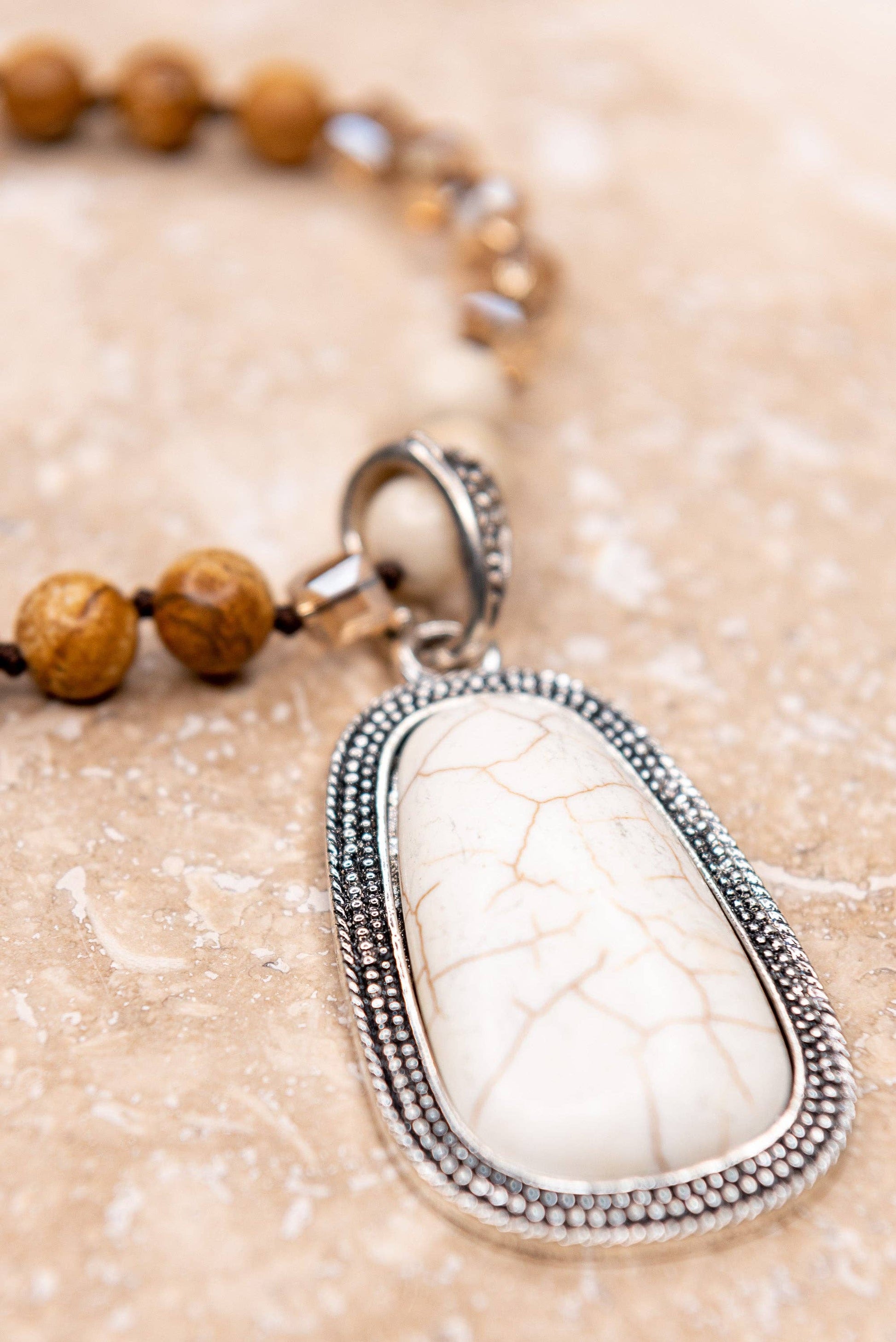 Necklace with a white stone pendant on a beige background