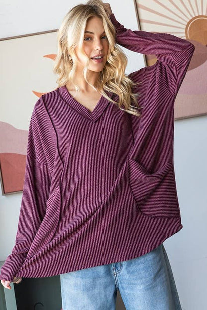 Woman wearing a purple sweater and blue jeans indoors with a neutral background