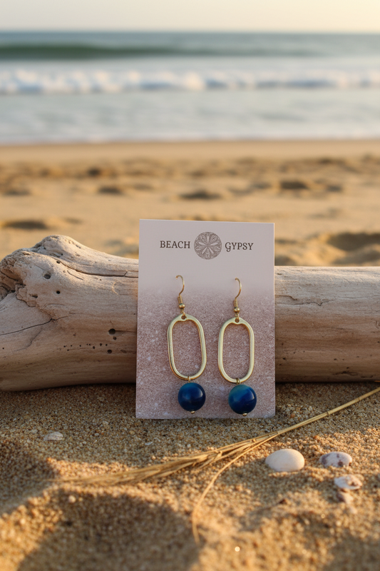 Blue stone dangle earrings on gold rectangle metal drop on beach 