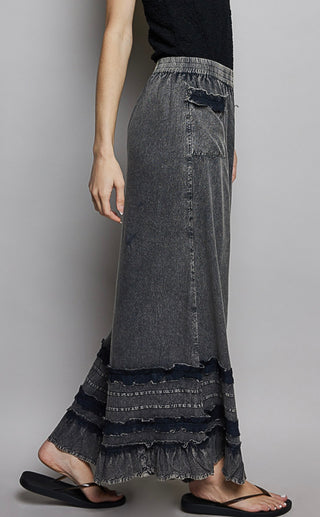 Long denim skirt with layered ruffle hem on a plain background