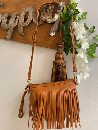 brown fringe crossbody bag hanging from gypsy sign