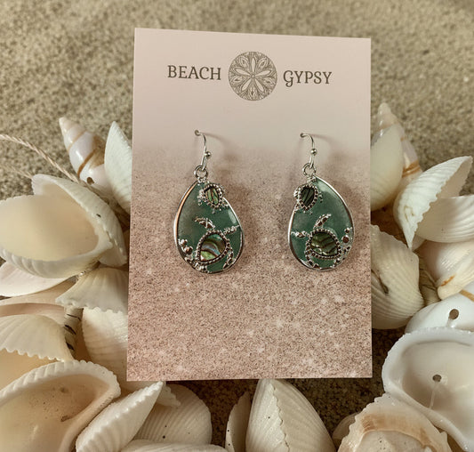 Pair of earrings on a 'Beach Gypsy' branded card surrounded by seashells.
