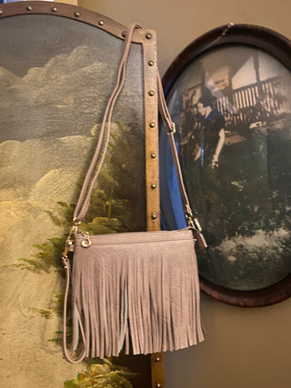 blush  fringe crossbody bag hanging near black and white photo