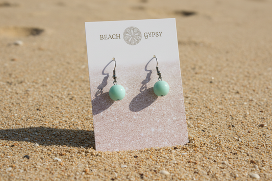 Amazonite green natural stone drop earrings on beach background 