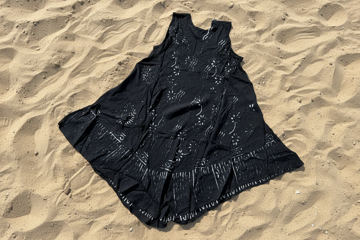 Black dress back view with white patterns on a beige tiled floor
