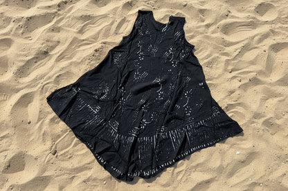 Black dress back view with white patterns on a beige tiled floor