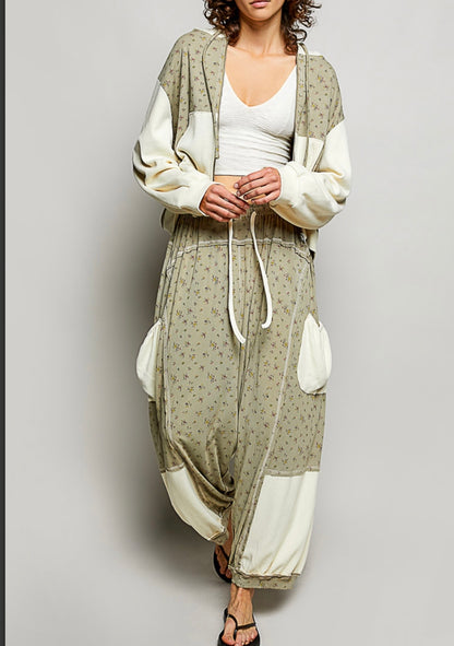 Woman wearing flowing sage colored ditzy flower print pants with cream patch pockets