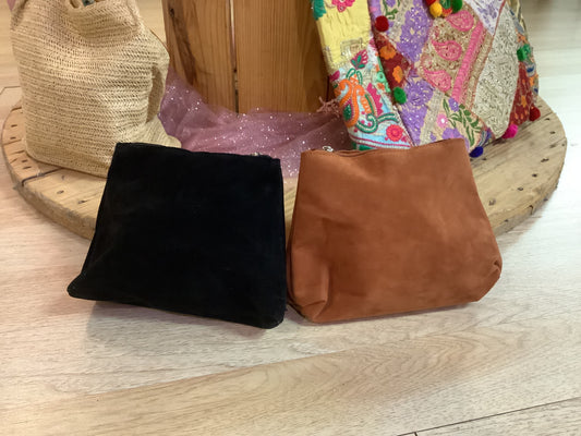 Black and brown bags on a wooden surface with colorful fabric in the background