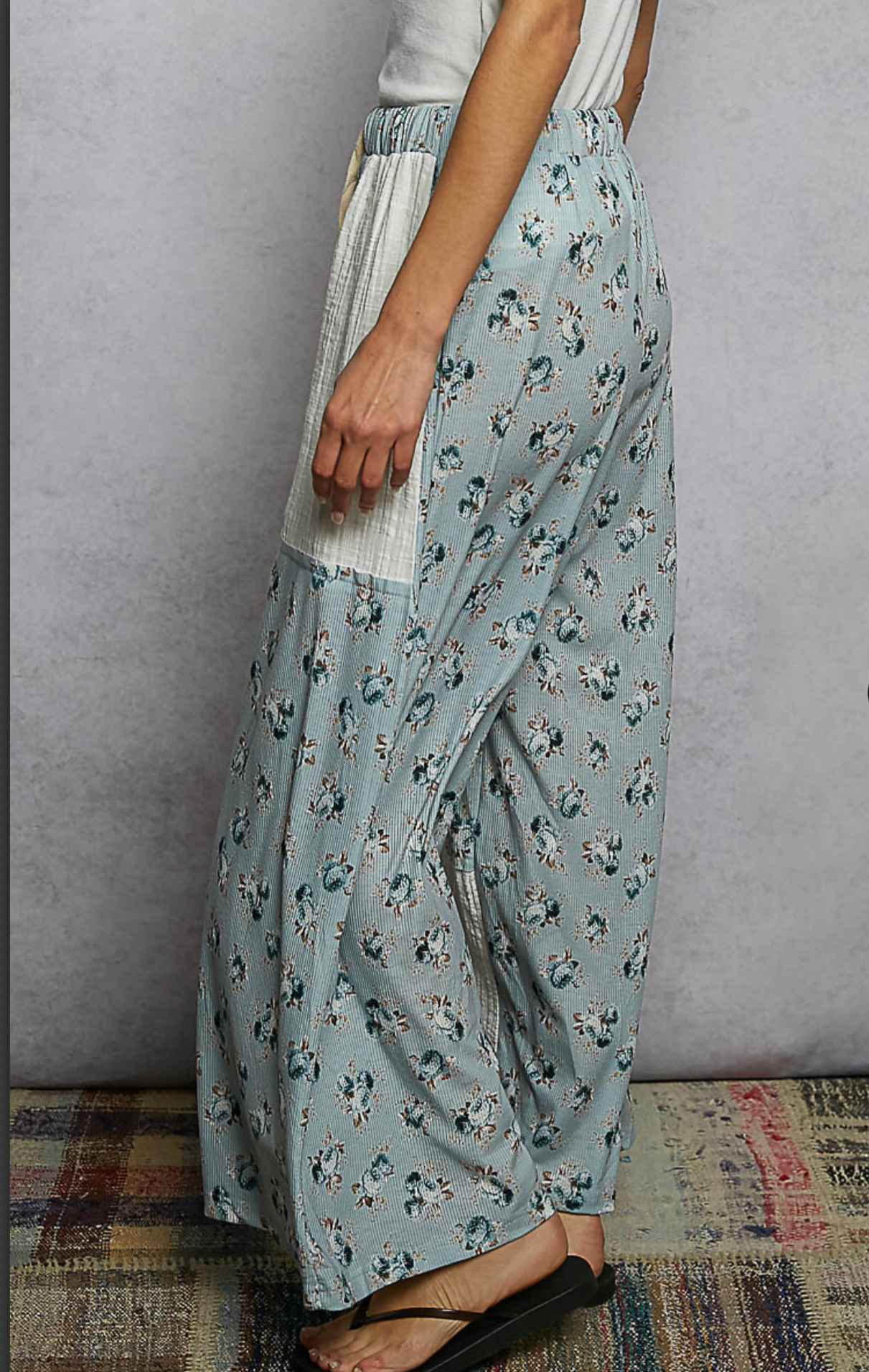 Woman wearing blue floral flowing pants with cream patches 