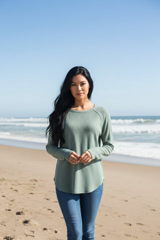 Woman wearing a green long-sleeve top on a beach background